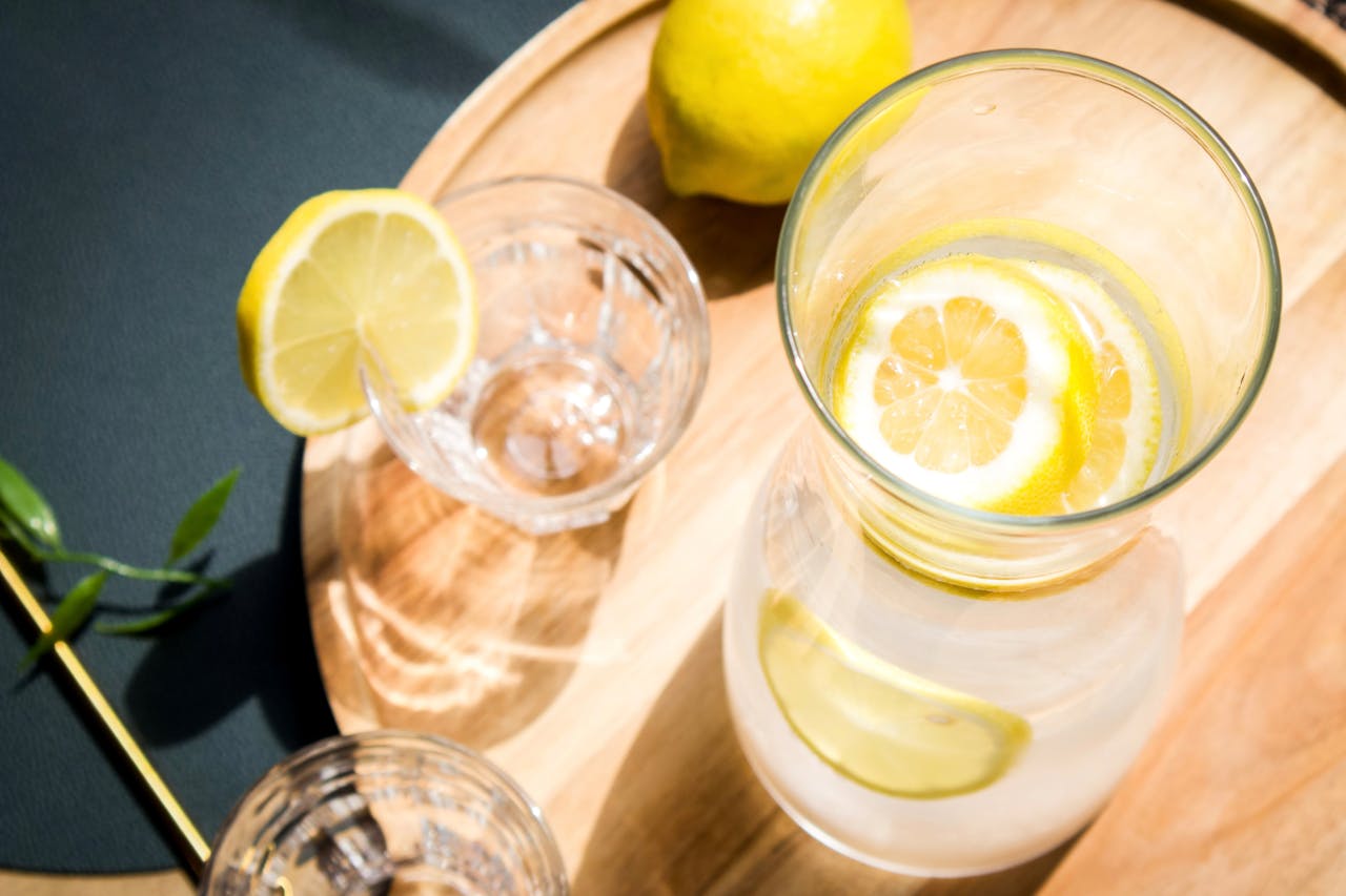Top view of lemon infused water and glass on a wooden tray, ideal for healthy lifestyle themes.